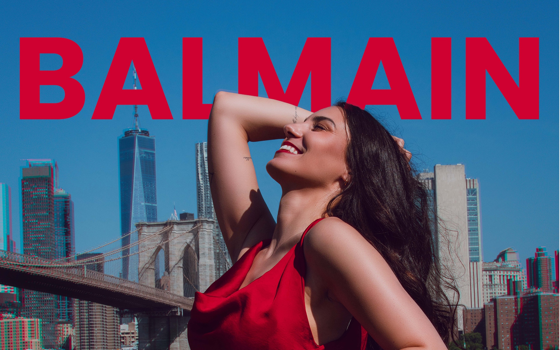 Woman in a red dress wearing a Balmain watch while standing in a New York City street.