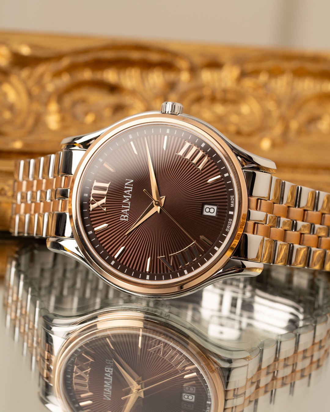 Gros plan sur une montre Balmain Beleganza avec flanc de bo&icirc;tier grav&eacute; et chiffres romains sur un cadran soleill&eacute;.