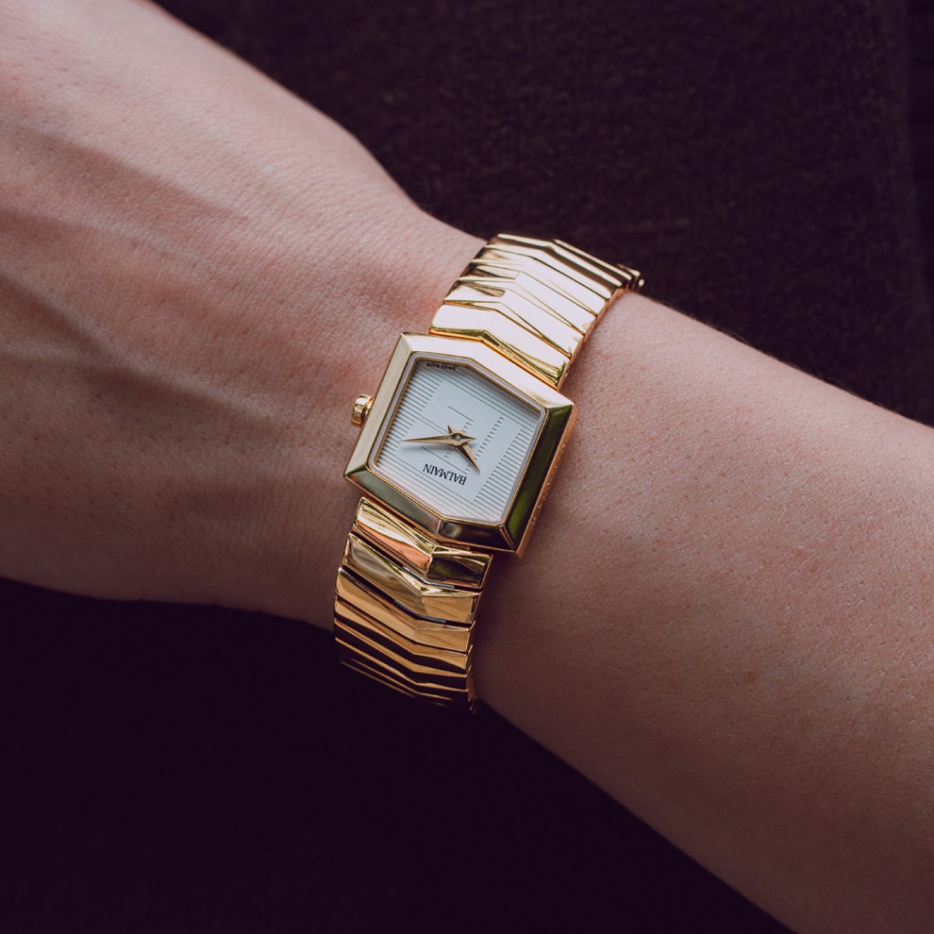 Lifestyle wrist shot of the Balmain Taffetas watch, showcasing its yellow gold PVD tones and elegant sporty design on a woman’s wrist.