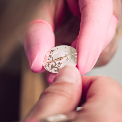 Elegant arabesque motifs and diamond embellishments inspired by Parisian Haute Couture Close-up of a watchmaker assembling a Balmain watch, highlighting Swiss craftsmanship