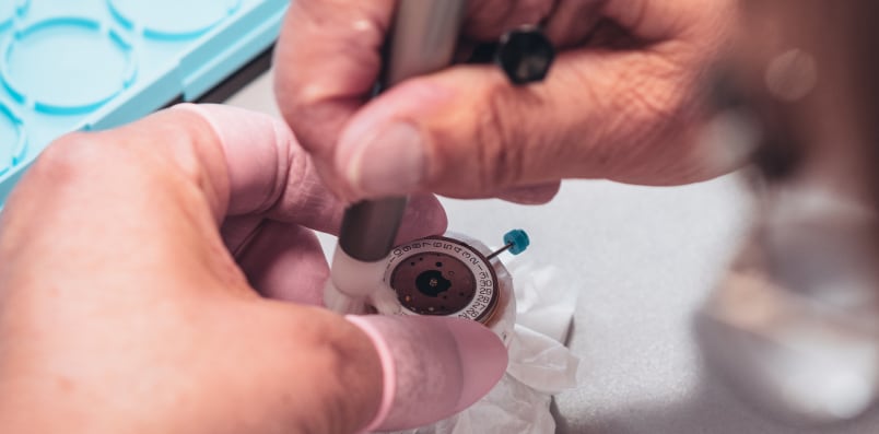 Balmain watch dial showcasing couture-inspired arabesque details and diamonds Detailed view of Swiss watchmaking artistry during Balmain assembly